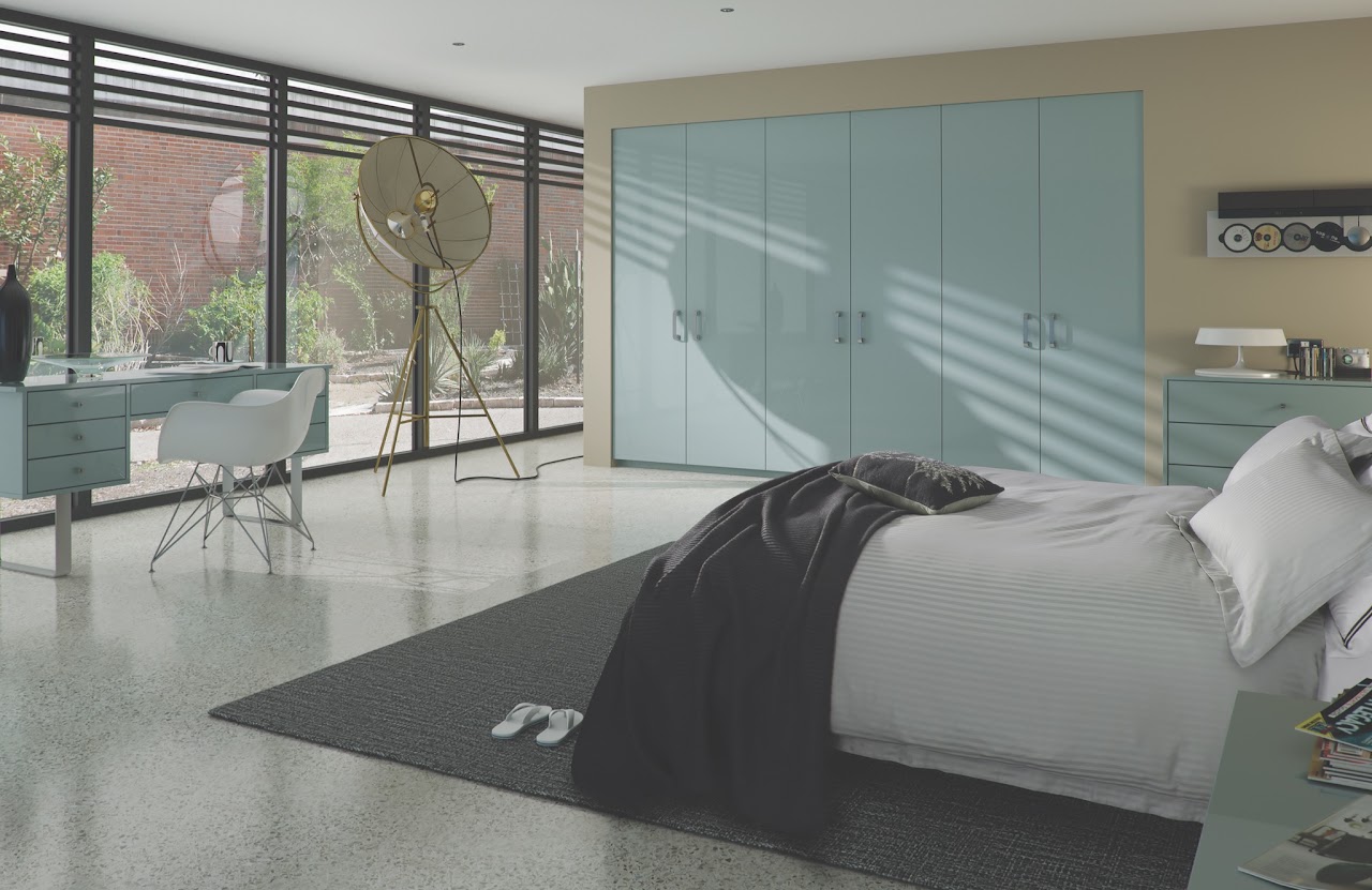 Spacious bedroom with bed, desk and soft blue fitted furniture