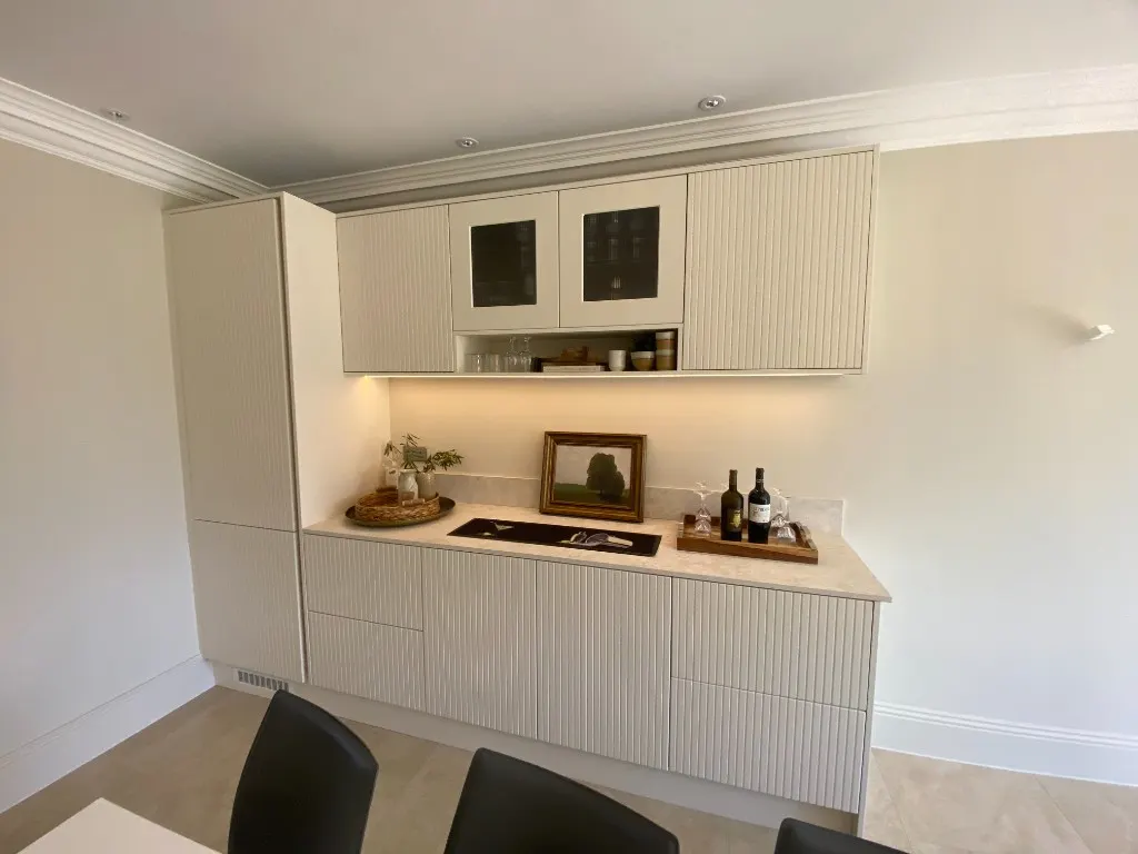 Full dining room with fluted cream bar wall and crystal chandelier