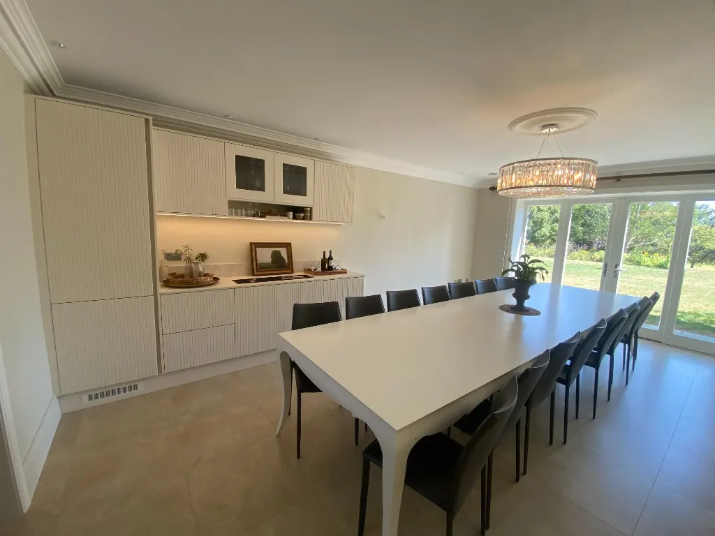 Long dining table beside cream fluted entertaining wall