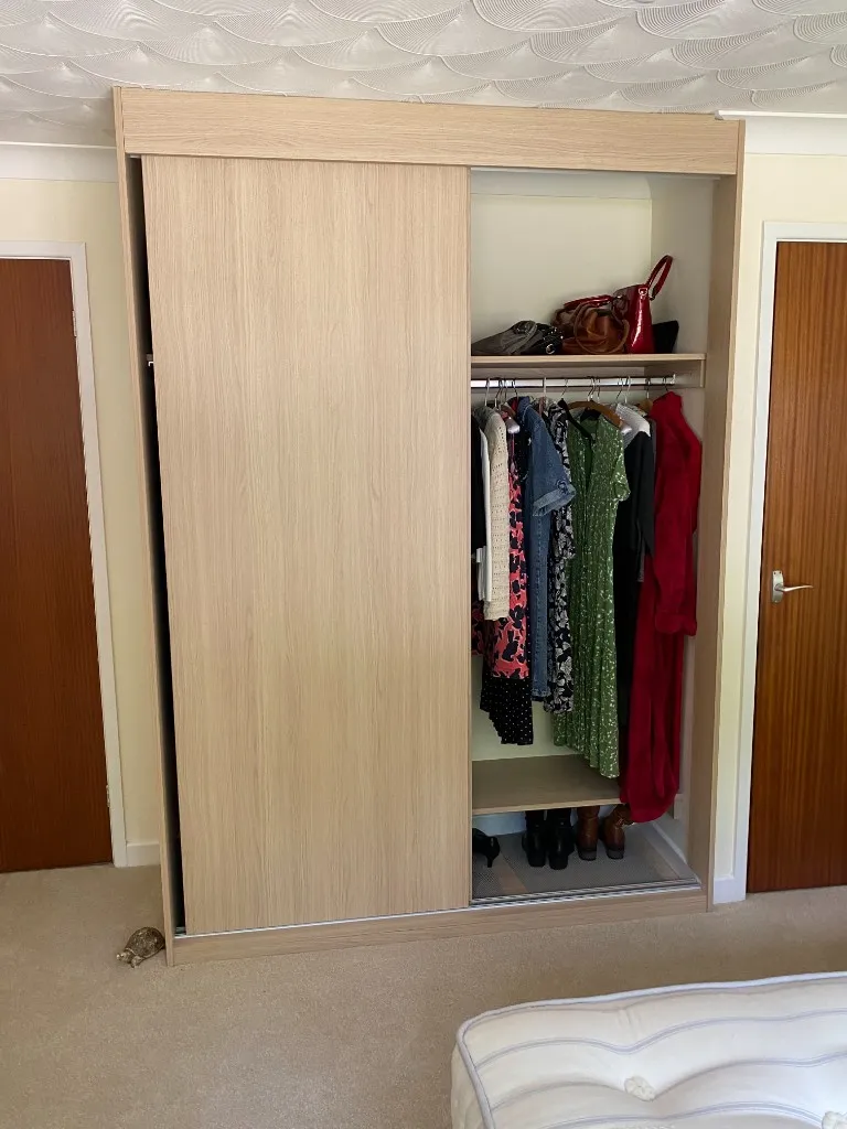 Light oak sliding wardrobe open showing handbags on top shelf