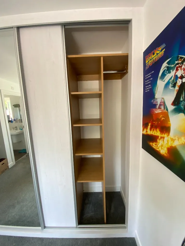 White-frame sliding wardrobe with right bay open showing shelves and rail