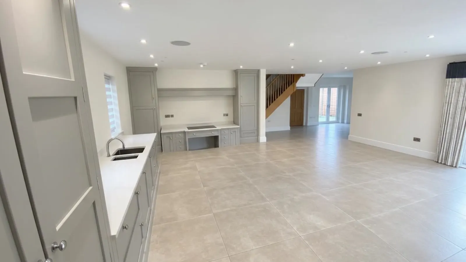 Modern open-plan kitchen with light grey cabinetry and island storage